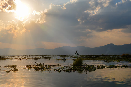 Lake Inle fishermen gathers his net while he paddles the boat with his leg