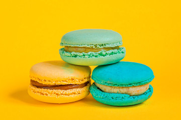 Sweet almond colorful unicorn pink blue yellow green macaron or macaroon dessert cake isolated on trendy yellow modern fashion background. French sweet cookie. Minimal food bakery concept Copy space