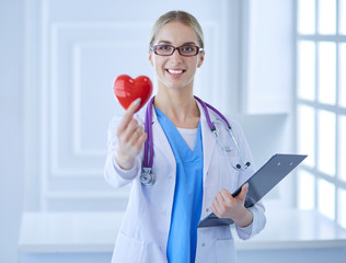 Female doctor with the stethoscope holding heart