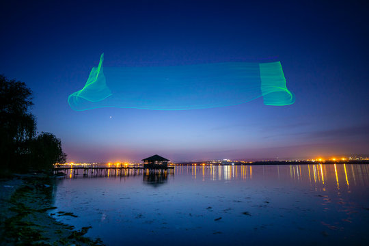 Fishing pier with lake house at night with drone imitating northern Aurora Borealis lights - Powered by Adobe