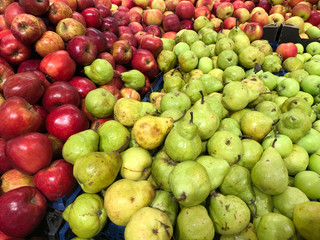 red apples and pear fruits in a supermarket, food and retail concept