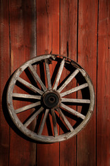 vintage wooden wagon wheel on red wooden rustic wall