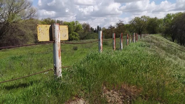 old rusty metal fence with tall green grass around