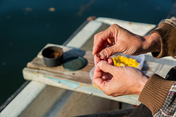 Close up of hands setting worm as bait on fishing hook. Man is holding fishing rod and line with...