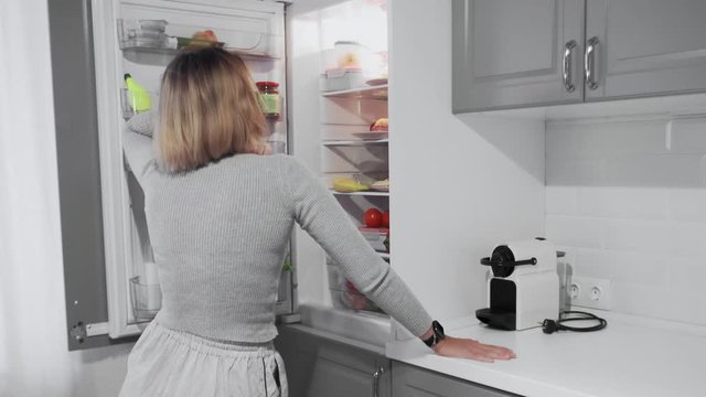 Young woman opening the fridge and choosing the best food for her diet