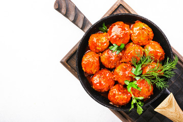 Meatballs with tomato sauce and spices in frying pan on white kitchen table background. Top View with copy space