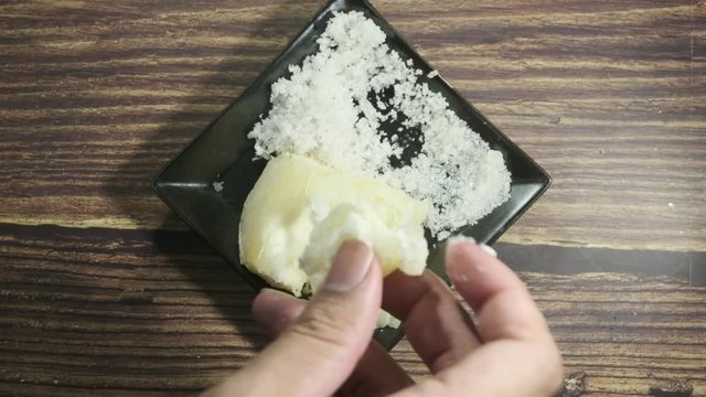 Top view of hand taking "ubi rebus" or steam cassava with sugar and grated coconut.