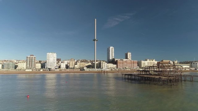 Seagulls fly by with Brighton West Pier ruin in foreground with new British Airways i360 in background