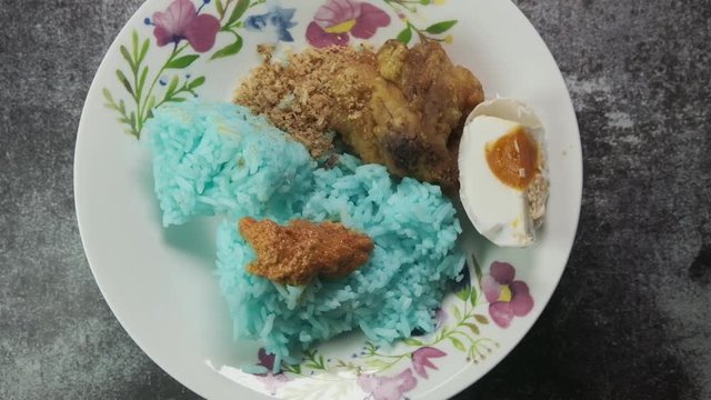 Rotating "nasi kerabu" on turntable. "Nasi kerabu" is blue-coloured rice is eaten with dried fish or fried chicken, crackers, pickles and other salads.