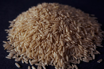 Pila de arroz integral marrón orgánico sobre fondo negro