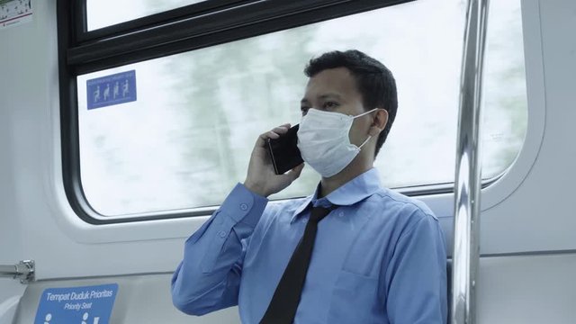 Asian businessman make a call and sits inside train