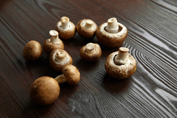 Mushrooms, group of fresh brown champignons scattered on a wooden background. Uncooked food ingredient