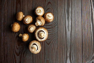Fototapeta na wymiar Mushrooms, fresh champignons scattered on a brown wooden background, top view. Raw food ingredient