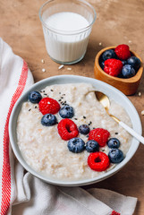 Breakfast oatmeal porridge with fresh berries and almond milk. Healthy vegan food concept. Top view. Copy space. Flat lay