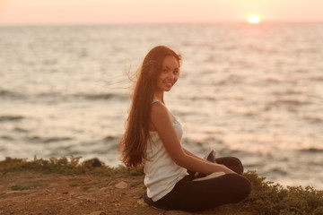 Fototapeta na wymiar silhouette of a girl doing yoga and mediation at sunset by the sea