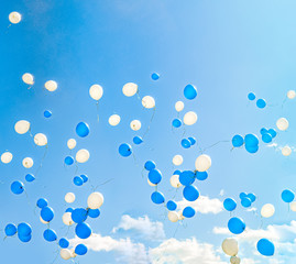 Blue and white flying balloons against blue sky with clouds background on sunny day. Low angle view. Holiday, celebration, Children's Day, wedding, graduation concept.Peace, love, freedom, purity idea