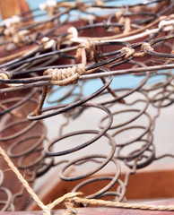 Rusted metal wire chair coils exposed in an antique wooden chair seat.  Rows of metal spirals with jute twine rope. Laid out in an array of pattern.  Chair is a vintage rocker.