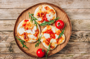 Pizzete. Home baked mini pizzas bolognese. Tomato sauce ,mozzarella cheese and minced meat. Rustic wooden table. Stay at home concept
