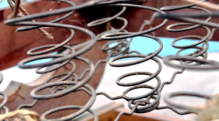 Rusted metal wire chair coils exposed in an antique wooden chair seat.  Rows of metal spirals with...