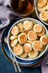 Trendy food - pancake cereal. Mini cereal pancakes in boul on blue cement background, top view. Copy space left for text.