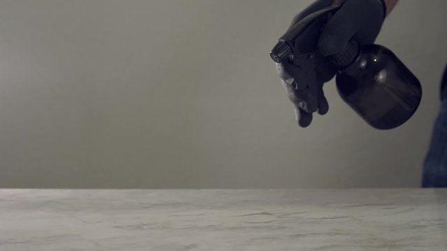 Desinfectando superficie de marmol  con un atomizador con liquido desinfectante y un trapo