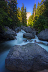 Gushing waters of the swirling Tuolumne river with huge river rocks in Yosemite Park, California.