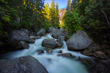 Gushing waters of the swirling Tuolumne river with huge river rocks in Yosemite Park, California.
