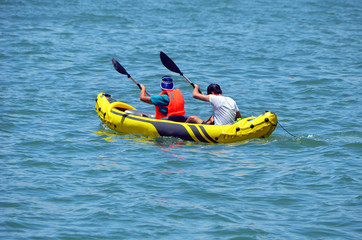 Fototapeta na wymiar two men kayaking on biscayne bay in a yellow inflatable kayak.
