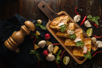 thai and mexican fusion food background of spicy chicken and mushroom tomyum quesadillas on wooden plate in dark tone, selective focused