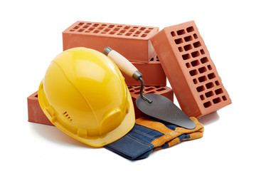 Stack of bricks with masonry trowel,  construction hard hat and gloves on white background. Construction concept.
