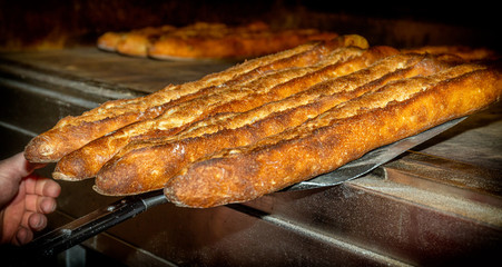 French baguettes getting out of the oven. The French sticks are crusty and golden. 