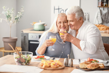 Obraz na płótnie Canvas Happy elderly couple having breakfast at home
