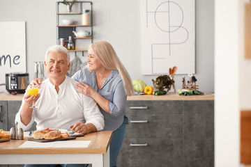 Happy elderly couple having breakfast at home