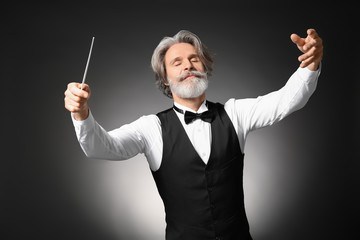 Senior male conductor on dark background