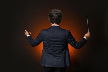 Senior male conductor on dark background - obrazy, fototapety, plakaty