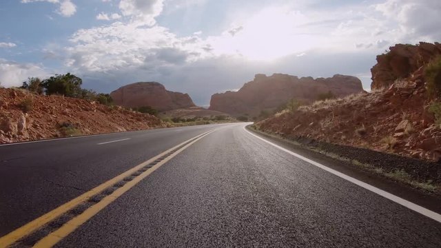 POV Driving a car on asphalt Arizona road with rocky mountains. Sunny sky with white clouds