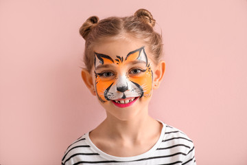 Funny little girl with face painting on color background
