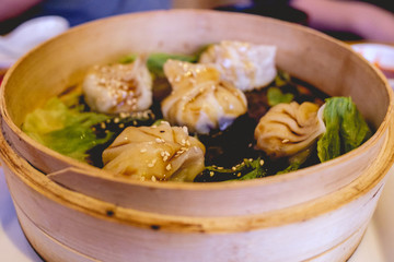 Closeup of dumplings with vegetables in a wood bowl with soy sauce