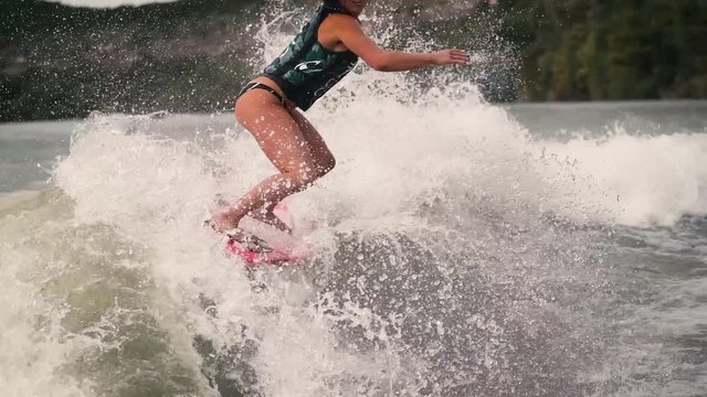 Wake surfer lands full spin three sixty in slow motion on lake with pink surf board