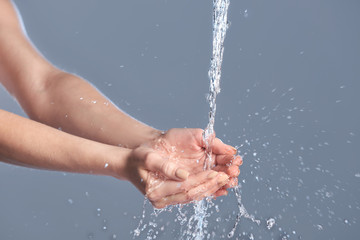 Woman washing hands against grey background