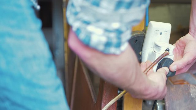 Man turn on light by plugging in socket wooden boat house interior