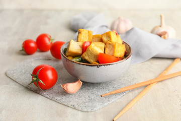 Bowl with tasty tofu cheese and vegetables on grey background