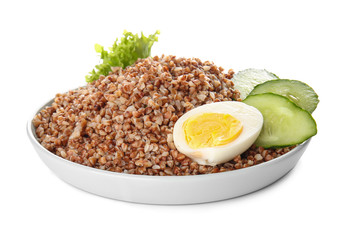 Plate with tasty buckwheat porridge, cucumber and eggs on white background