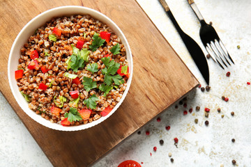 Bowl of tasty buckwheat porridge and vegetables on white background