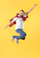 Obraz premium Energetic young man jumping with headphones, expressing joy and freedom, isolated on a bright yellow background