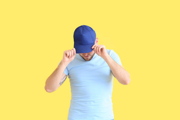 Handsome man in stylish cap on color background