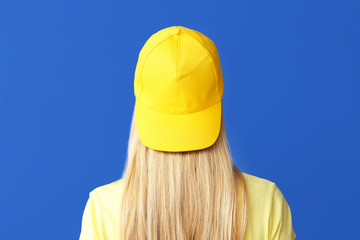 Beautiful young woman in stylish cap on color background © Pixel-Shot