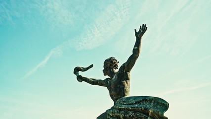 Dramatic low angle shot of the athletic torch bearer, one of the side figures of the Liberty Statue in Budapest, Hungary. 