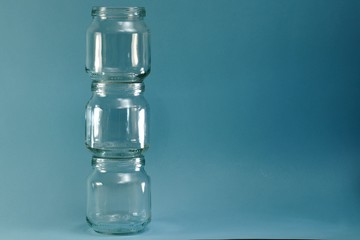 Vertical row of glass jars on the left on a horizontal blue background.