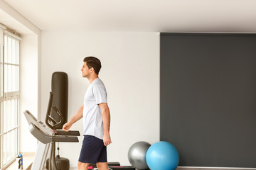 Young man training on treadmill in gym